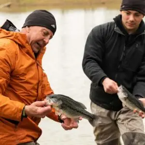 Stocking the lake at Crescent - Two men holding fish.